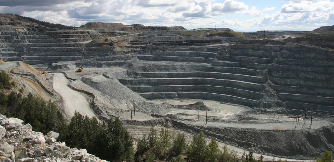 Open-pit mine with terraced benches under a cloudy sky
