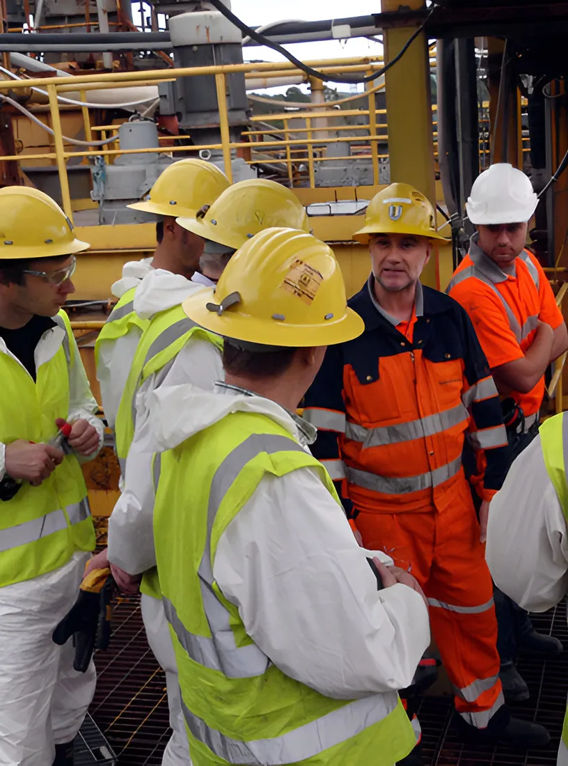 Group of workers in hard hats and high-visibility clothing at an industrial site