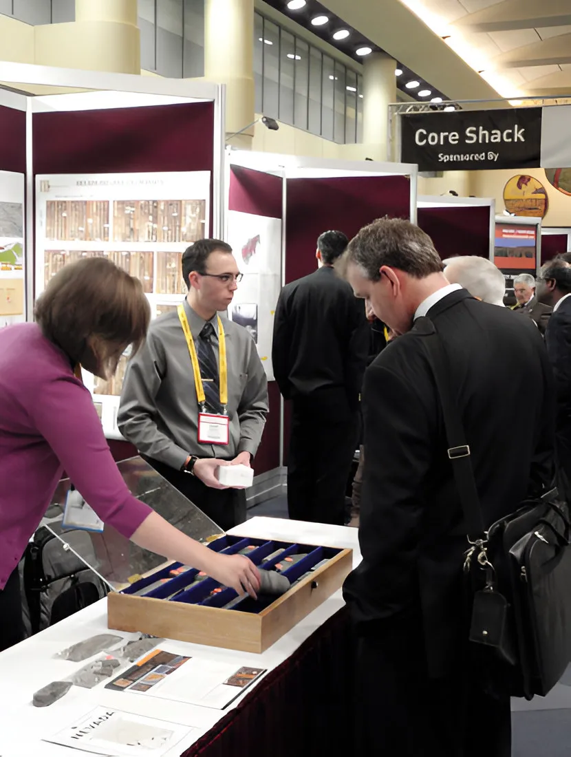 Visitors at an exhibition stand with a tray of core samples