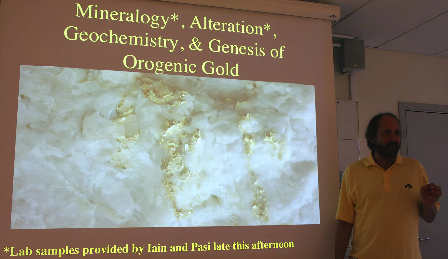 Richard Goldfarb lecturing beside a slide on the genesis of orogenic gold