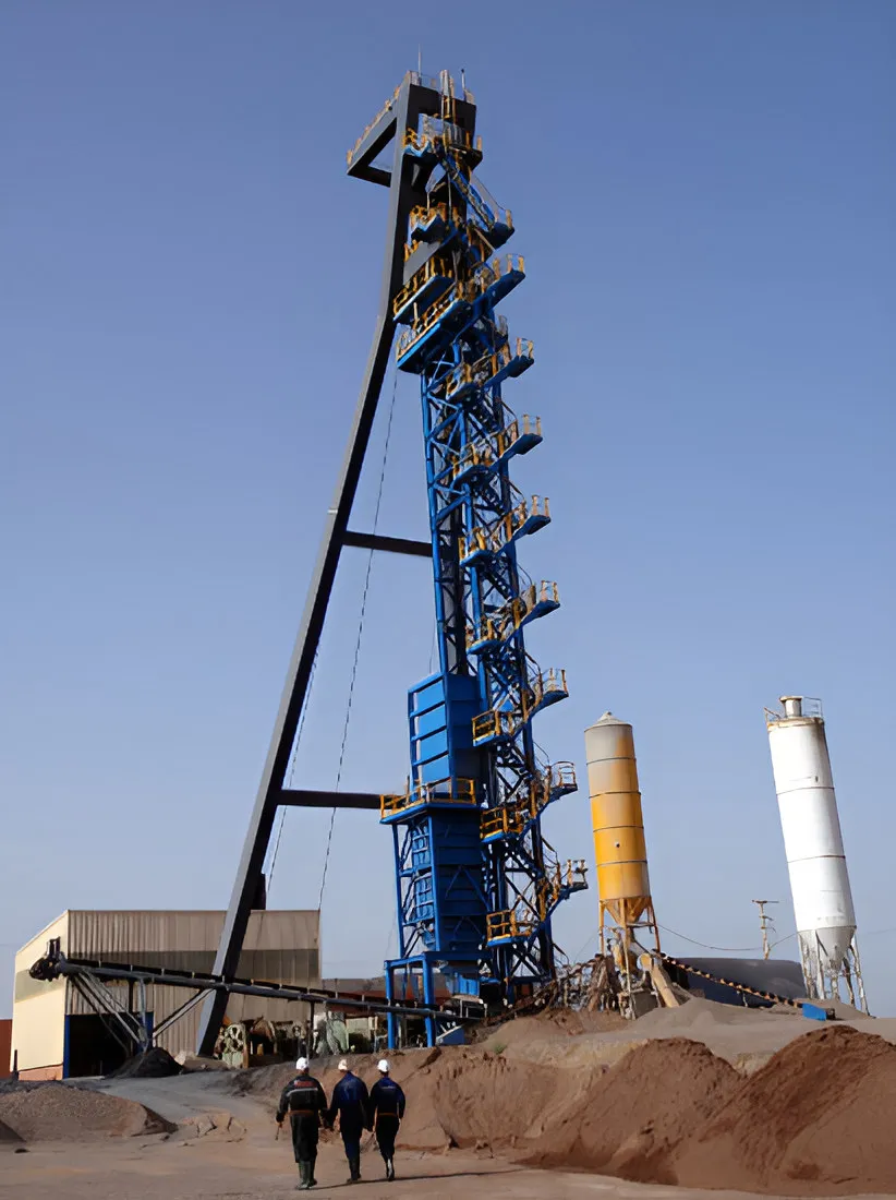 Blue steel mine headframe with silos and two workers walking below