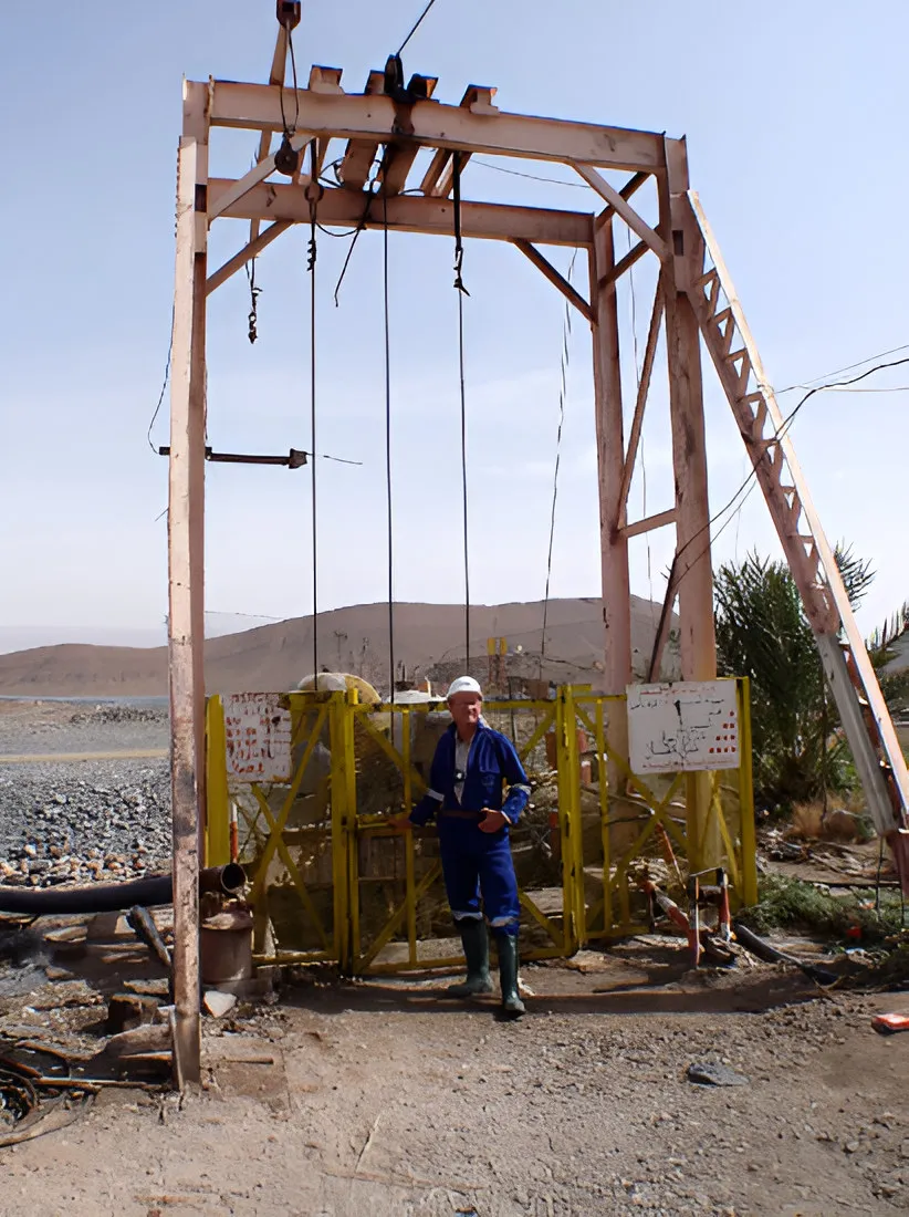 Old wooden mine hoisting frame with a worker standing in front