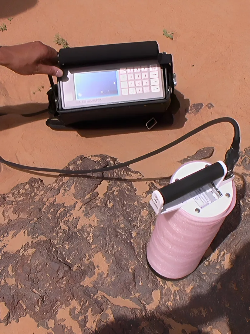Handheld scintillometer on red-brown ground