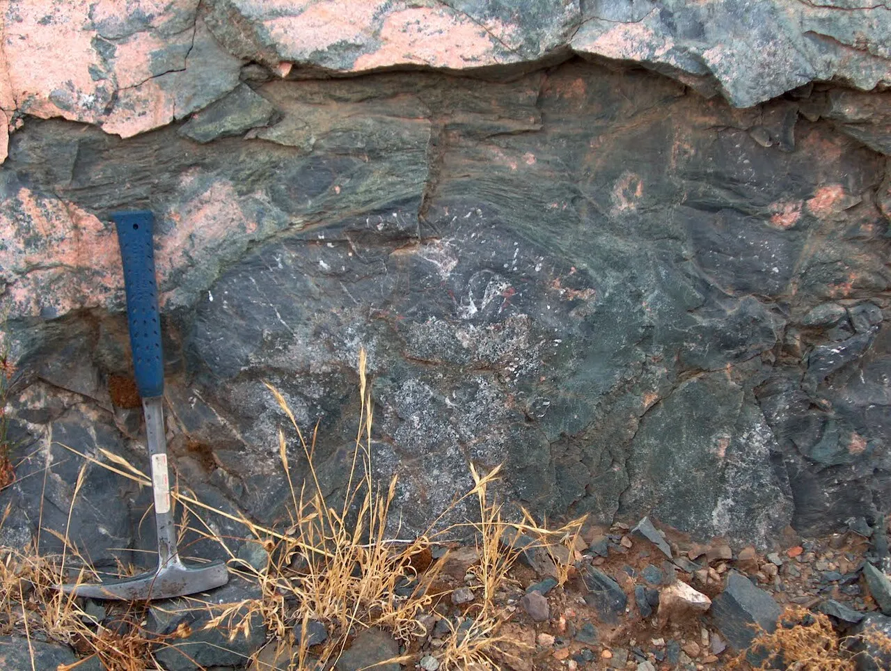 Pillow lava outcrop with a geological hammer for scale, Spain