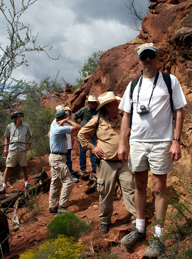Group of people standing on a red rock slope in the field